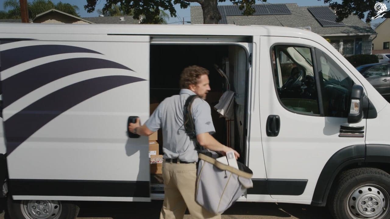A delivery person steps out of a postal van carrying letters.