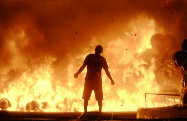 A figure stands in front of a burning Carnival warehouse in the campaign film.